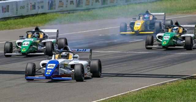 A pack of F4 Indian Championship cars fighting through a corner