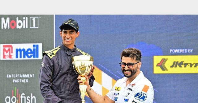 An F4 Indian Championship driver is presented with his trophy on the podium