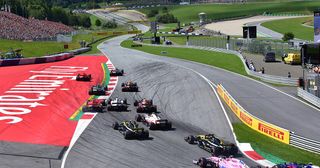The Formula 1 field sweeping through turn one at the start of the 2018 Austrian Grand Prix